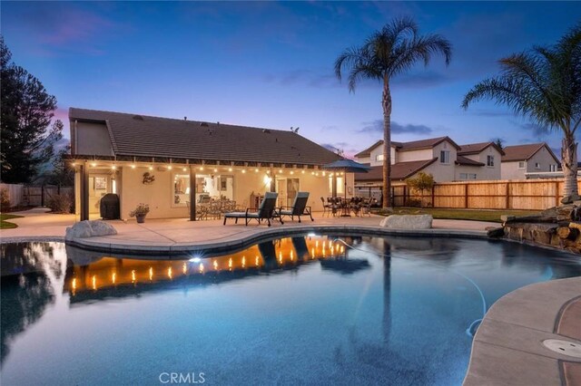 pool at dusk with a patio