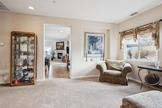 sitting room with light carpet and a fireplace