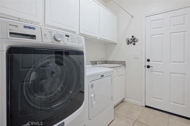 laundry area featuring cabinets, light tile patterned floors, washing machine and clothes dryer, and sink