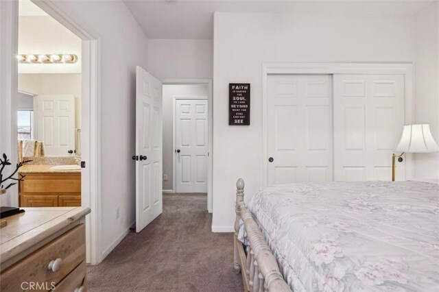 carpeted bedroom with sink, a closet, and ensuite bath