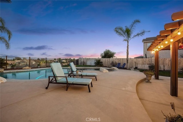 pool at dusk with a patio area and a pergola