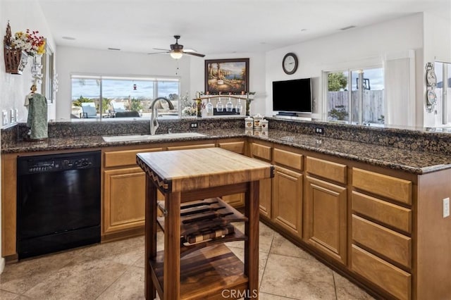 kitchen featuring light tile patterned floors, ceiling fan, dishwasher, dark stone counters, and sink