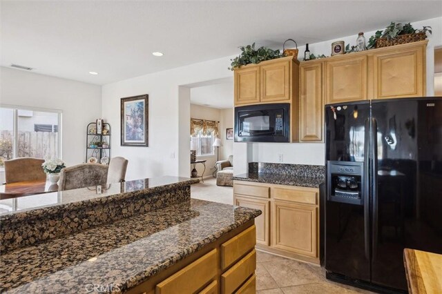 kitchen with light tile patterned floors, black appliances, and dark stone counters