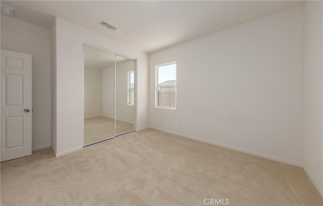 unfurnished bedroom with a closet and light carpet