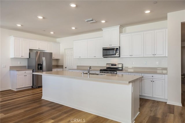 kitchen with sink, an island with sink, stainless steel appliances, and white cabinetry