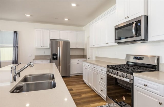 kitchen with appliances with stainless steel finishes, dark hardwood / wood-style flooring, white cabinetry, and sink