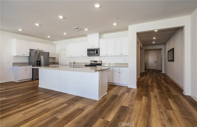 kitchen with white cabinetry, an island with sink, appliances with stainless steel finishes, dark hardwood / wood-style floors, and sink