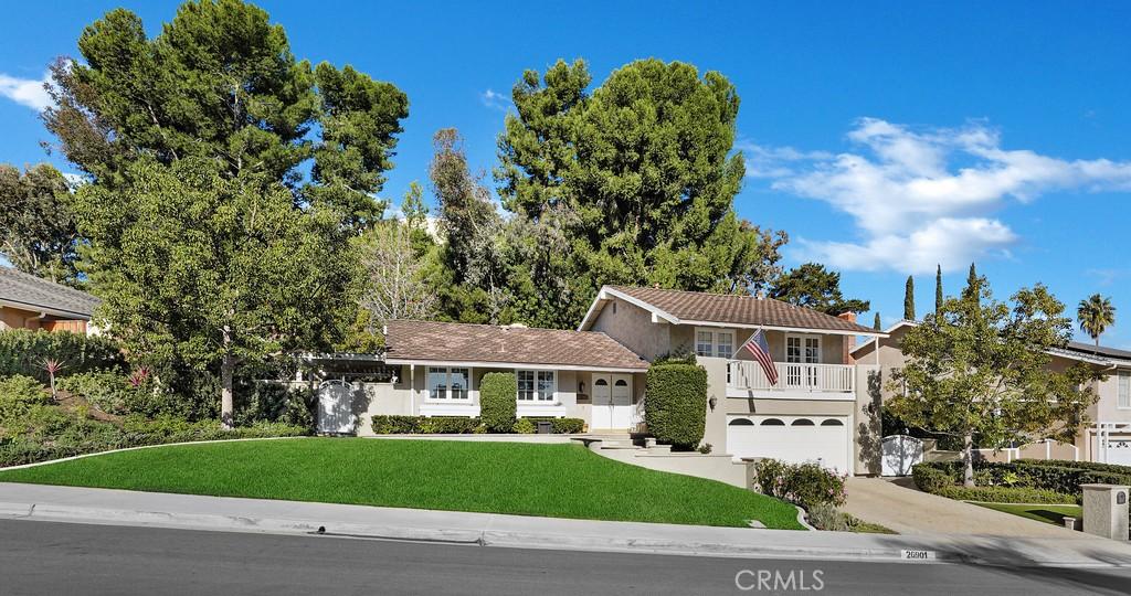 split level home with a front lawn, a garage, and a balcony