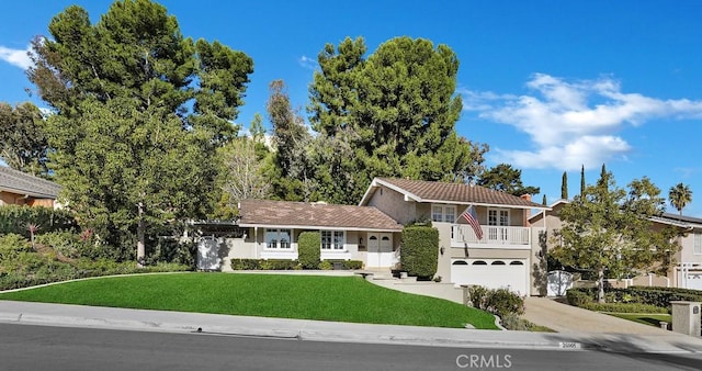 split level home with a front lawn, a garage, and a balcony