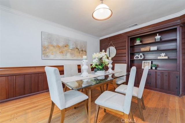 dining space with light wood-type flooring and ornamental molding