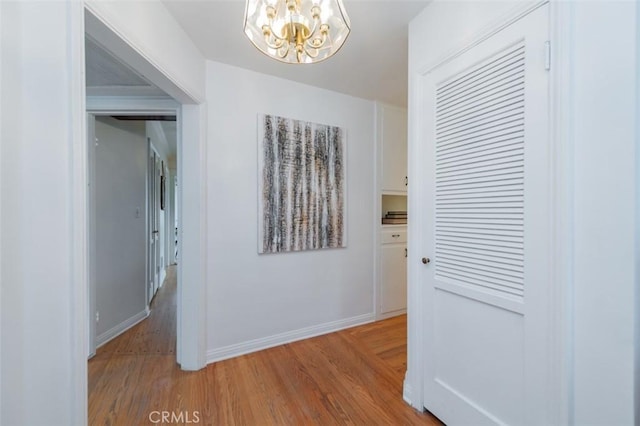 hallway with hardwood / wood-style flooring and a chandelier