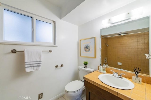 bathroom with toilet, vanity, and tiled shower