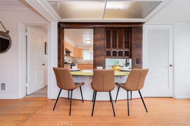 dining area with ornamental molding and light hardwood / wood-style floors