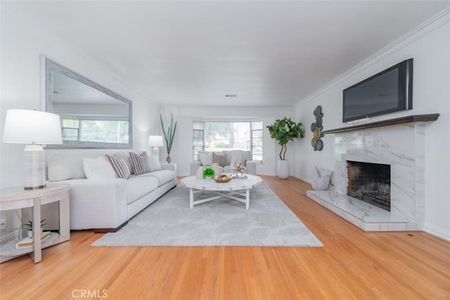 living room featuring hardwood / wood-style flooring, ornamental molding, and a fireplace