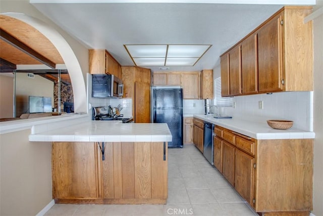 kitchen featuring tile counters, stainless steel appliances, sink, backsplash, and kitchen peninsula