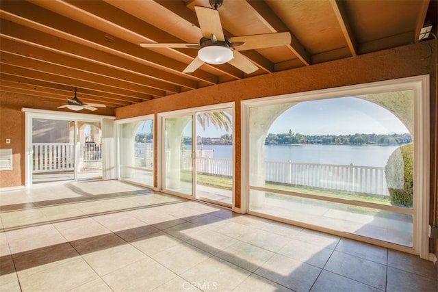 unfurnished sunroom featuring ceiling fan, a healthy amount of sunlight, a water view, and beamed ceiling