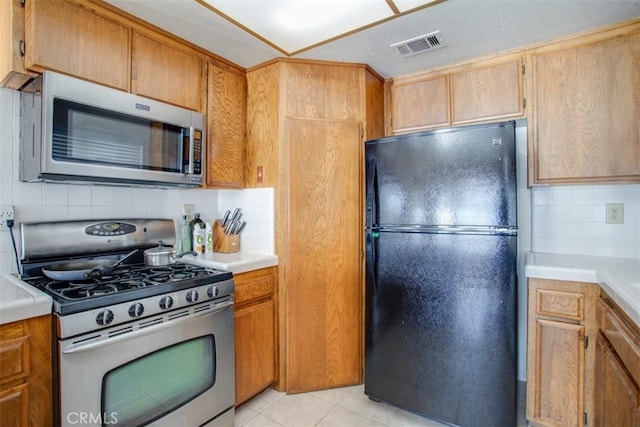 kitchen with tasteful backsplash, light tile patterned floors, and appliances with stainless steel finishes