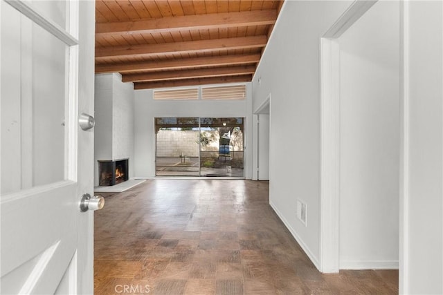 unfurnished living room with wooden ceiling, a large fireplace, and beamed ceiling