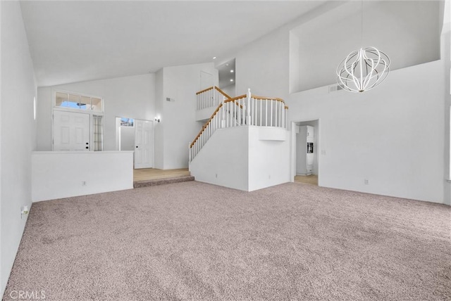 unfurnished living room with a chandelier, carpet floors, and high vaulted ceiling