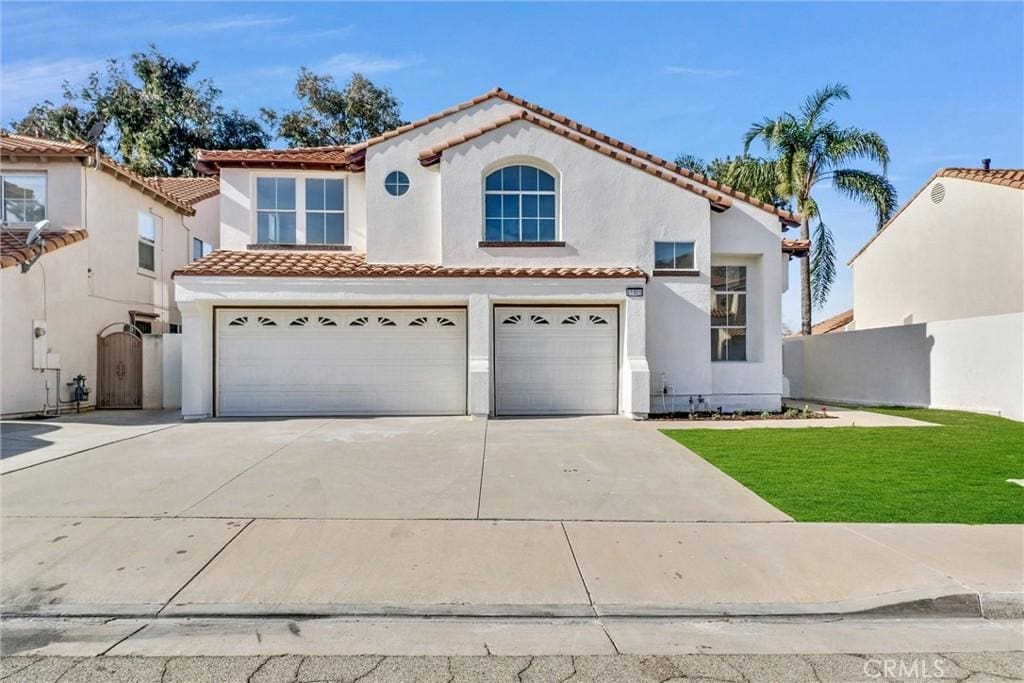 mediterranean / spanish-style house featuring a garage and a front lawn