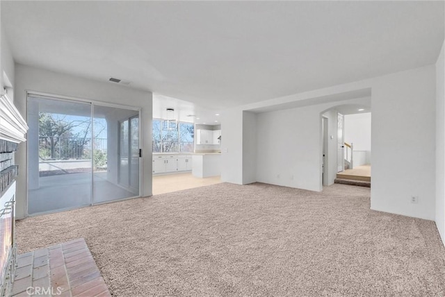 interior space with light carpet and a brick fireplace