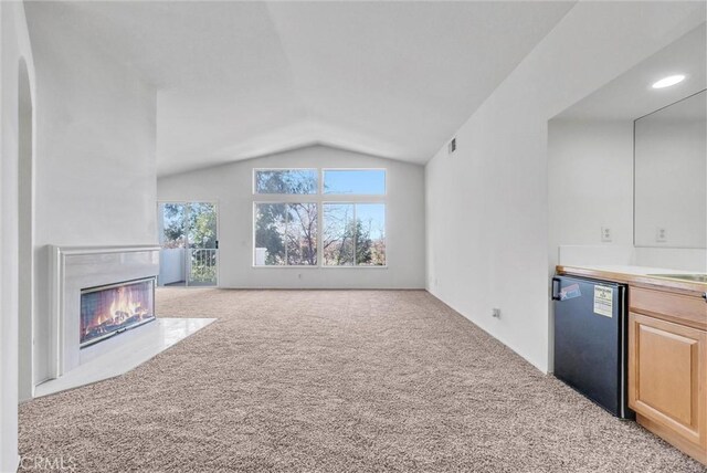 unfurnished living room with light carpet, lofted ceiling, and sink