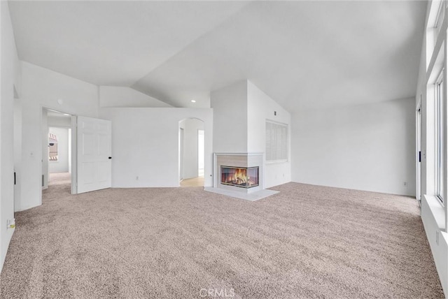 unfurnished living room with carpet, vaulted ceiling, and a multi sided fireplace