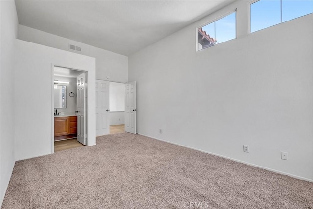 unfurnished bedroom with sink, connected bathroom, and light carpet