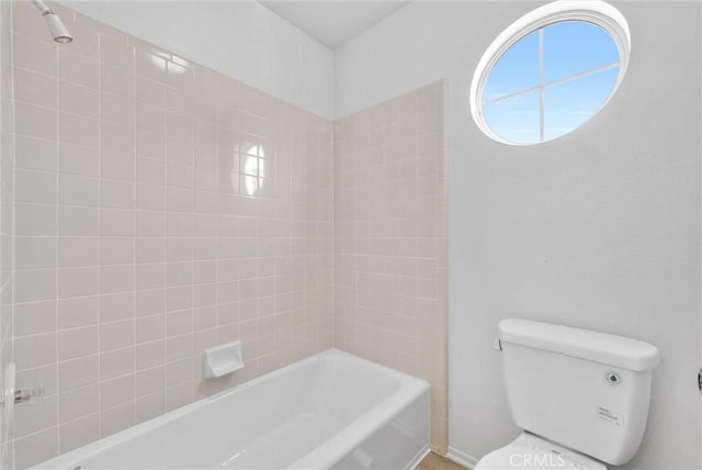 bathroom with toilet and tiled shower / bath