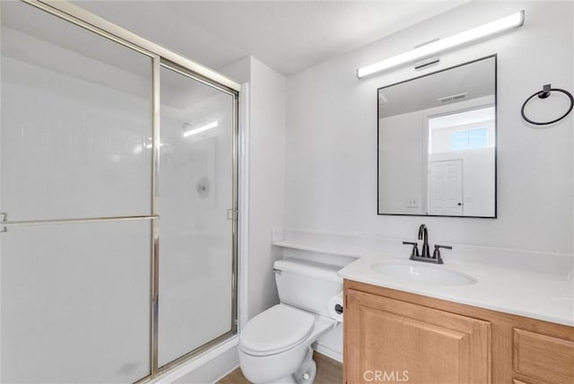 bathroom with an enclosed shower, vanity, and toilet