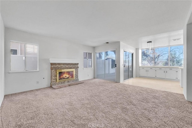 unfurnished living room with light carpet and a brick fireplace