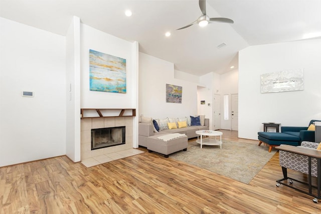 living room with ceiling fan, lofted ceiling, a fireplace, and light hardwood / wood-style flooring