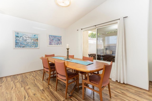 dining room with vaulted ceiling and light hardwood / wood-style floors