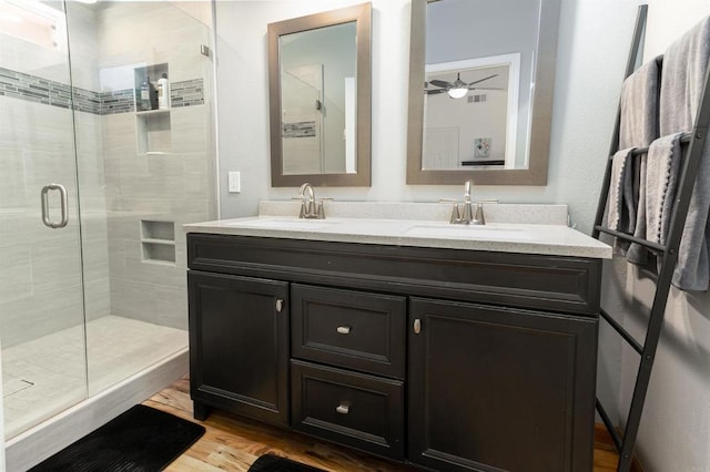 bathroom featuring ceiling fan, wood-type flooring, a shower with shower door, and vanity