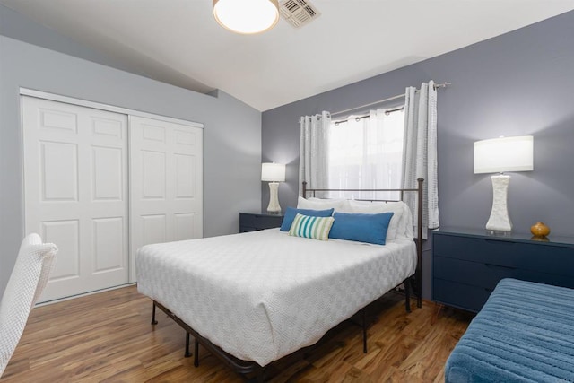 bedroom featuring vaulted ceiling, a closet, wood finished floors, and visible vents