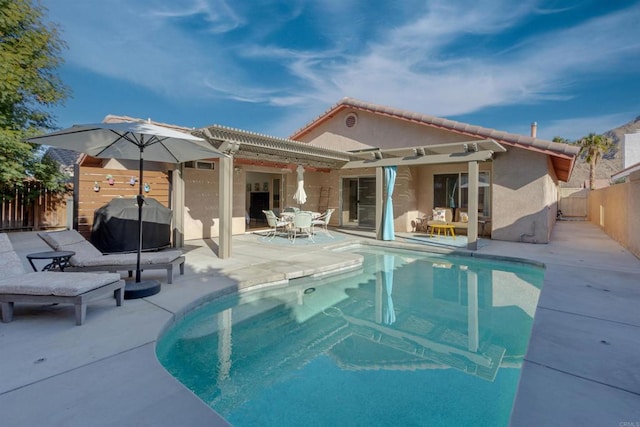 back of property featuring a fenced in pool, a patio, a fenced backyard, a tiled roof, and stucco siding