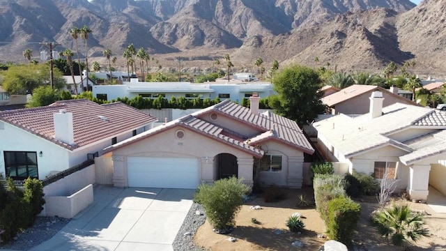 view of front of house featuring a tile roof, stucco siding, concrete driveway, an attached garage, and a mountain view