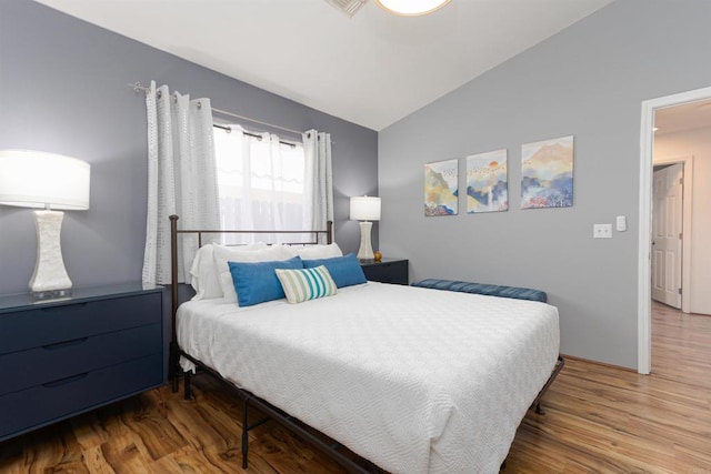 bedroom with lofted ceiling and wood finished floors