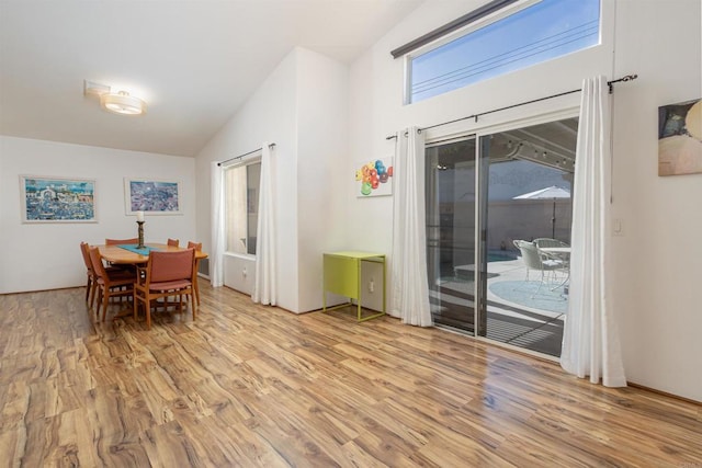 dining area with light wood-type flooring and vaulted ceiling