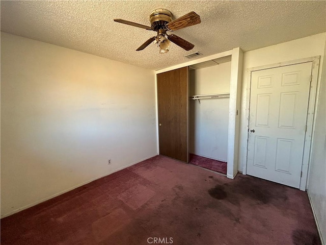 unfurnished bedroom with ceiling fan, a closet, dark carpet, and a textured ceiling