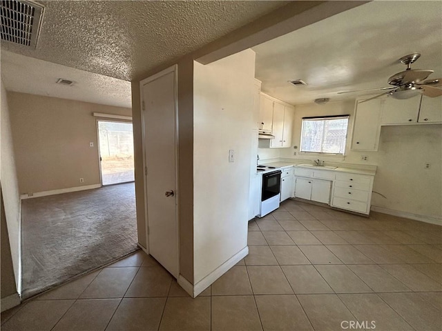 kitchen with light tile patterned floors, ceiling fan, electric range oven, white cabinets, and sink