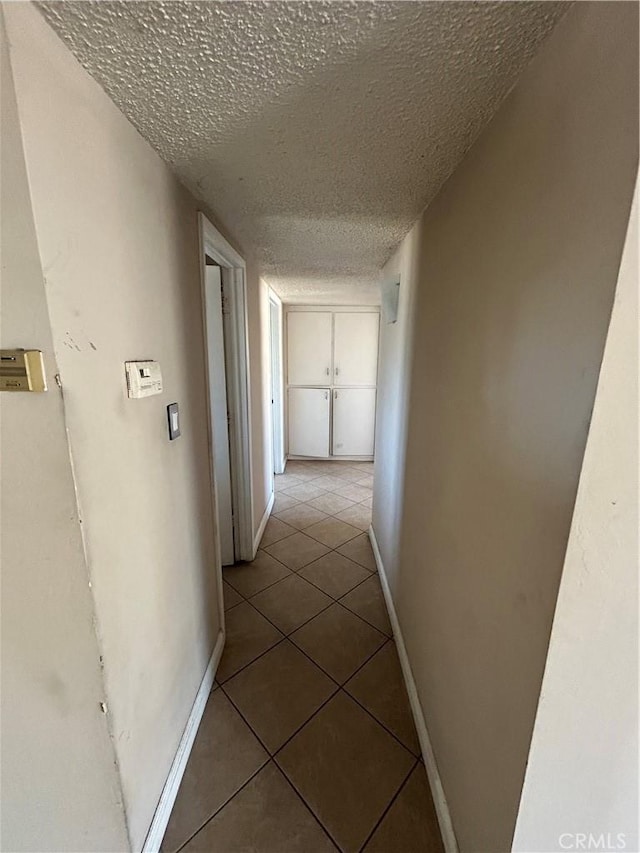 hall with tile patterned flooring and a textured ceiling