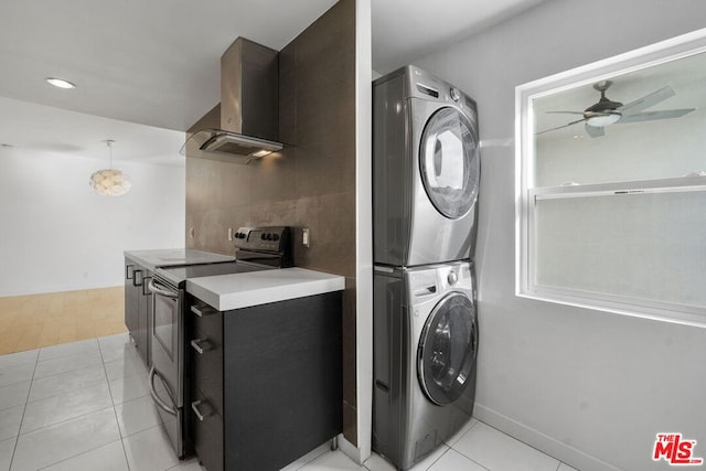 clothes washing area with ceiling fan, light tile patterned floors, and stacked washing maching and dryer