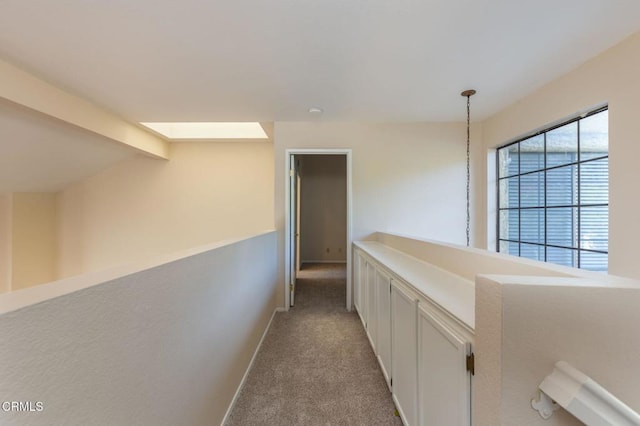 corridor with beam ceiling, light colored carpet, and plenty of natural light