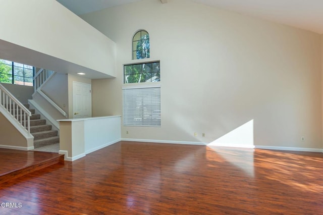 unfurnished living room featuring high vaulted ceiling, beam ceiling, and dark wood-type flooring