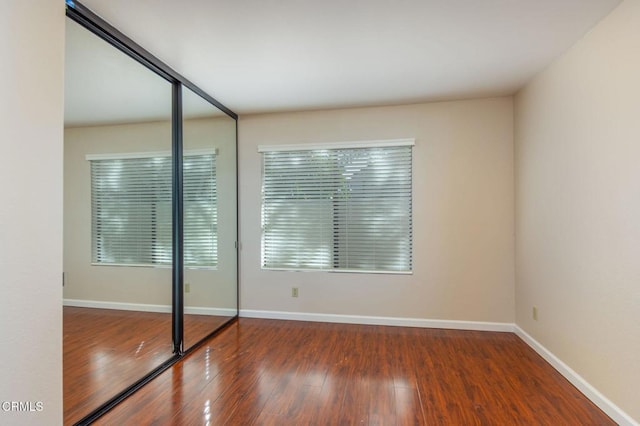 unfurnished bedroom featuring baseboards, dark wood finished floors, and a closet