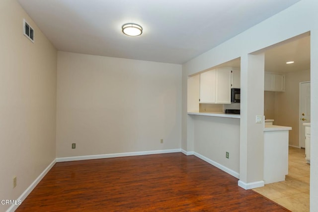 spare room with baseboards, visible vents, and wood finished floors