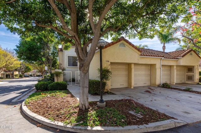 view of front of property with a garage, driveway, a tiled roof, and stucco siding