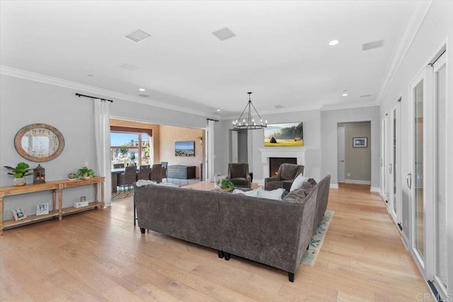 living room featuring light hardwood / wood-style flooring, ornamental molding, and an inviting chandelier