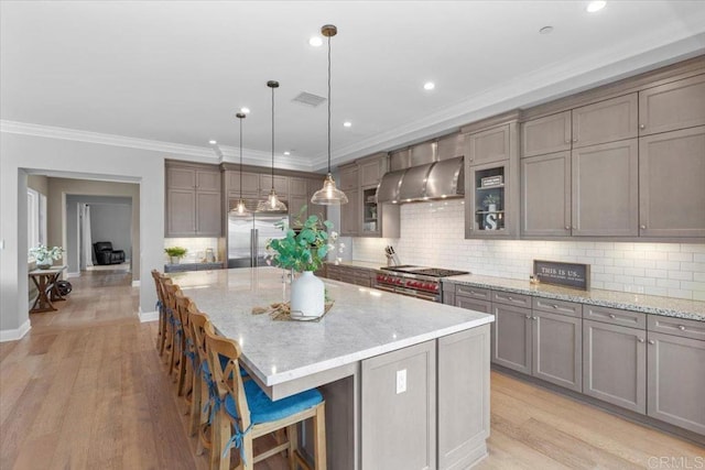 kitchen featuring pendant lighting, premium appliances, wall chimney exhaust hood, tasteful backsplash, and a large island